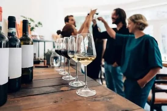 Colleagues at a wine tasting around a long wooden table